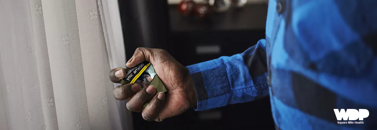 A man's hand crushing a cigarette packet.