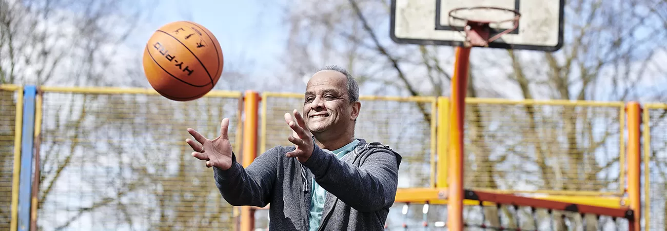 A man on a basketball court throwing an orange basketball in the air.