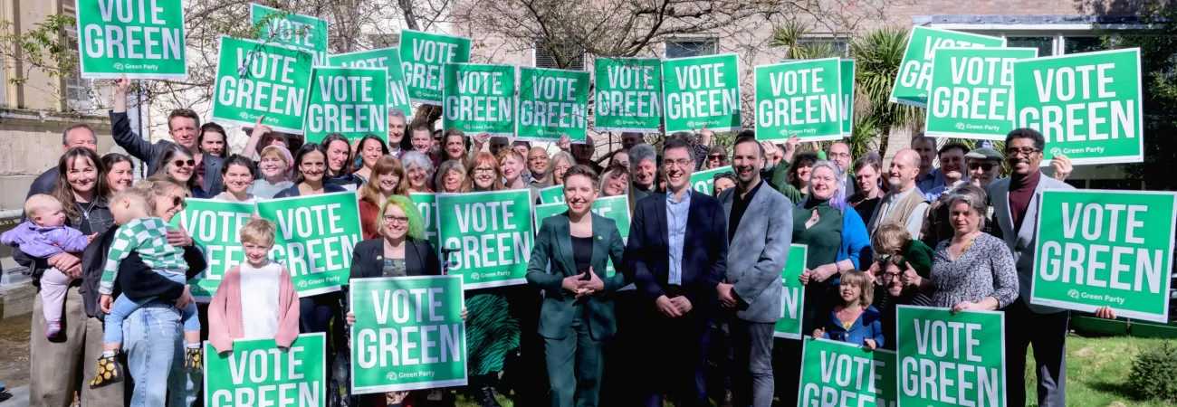 A large group of Green Party activists holding banners.